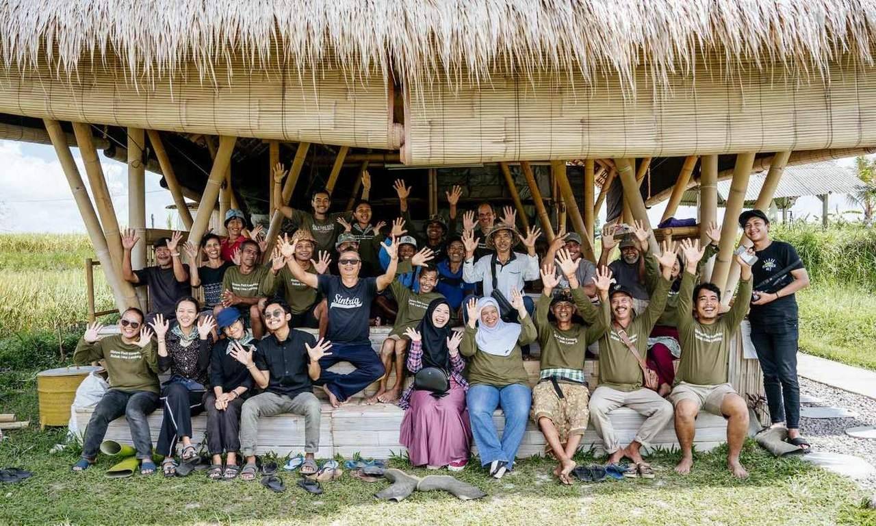 The Astungkara Way field team and farmers waving from the bamboo learning center
