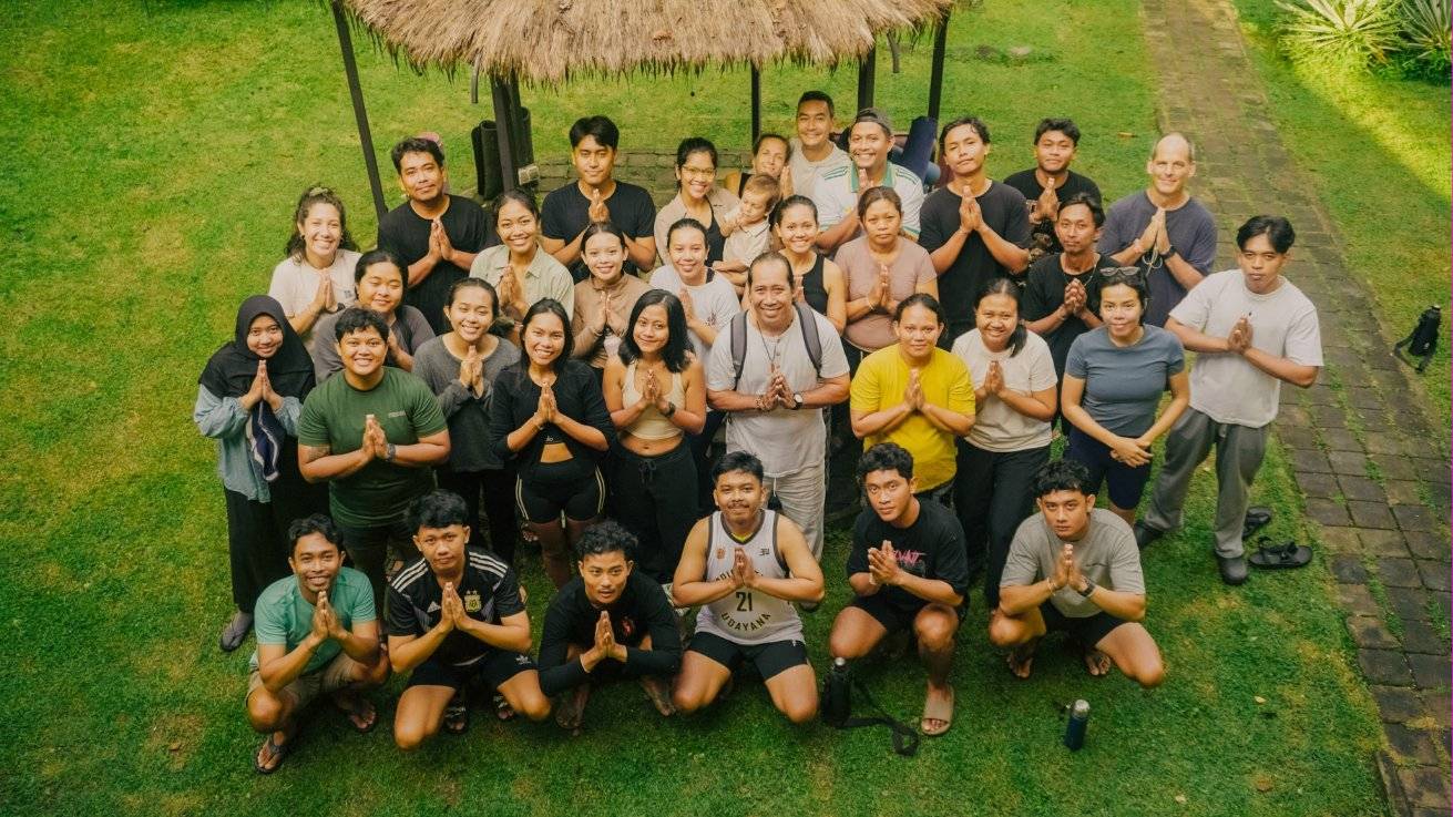 The Astungkara Way team together on the lawn, hands pressed in greeting