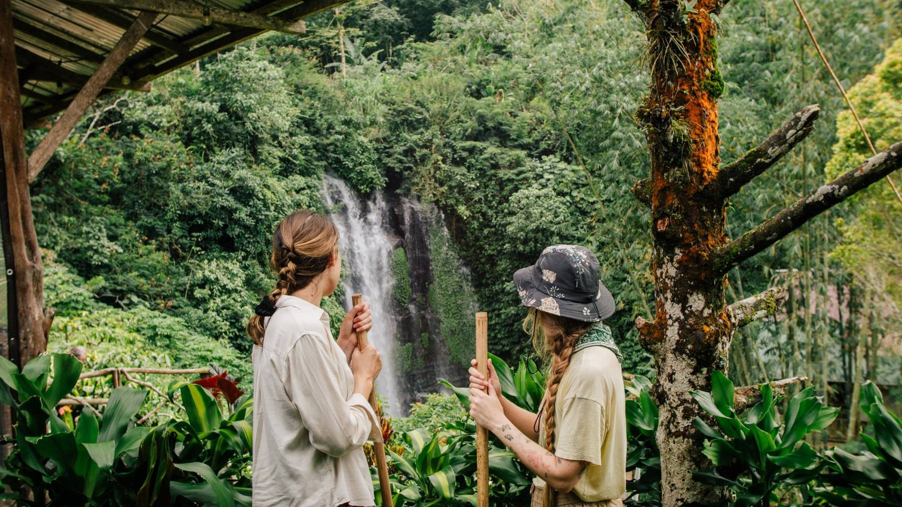 Two pilgrims with bamboo staffs looking at the Golden Valley waterfall