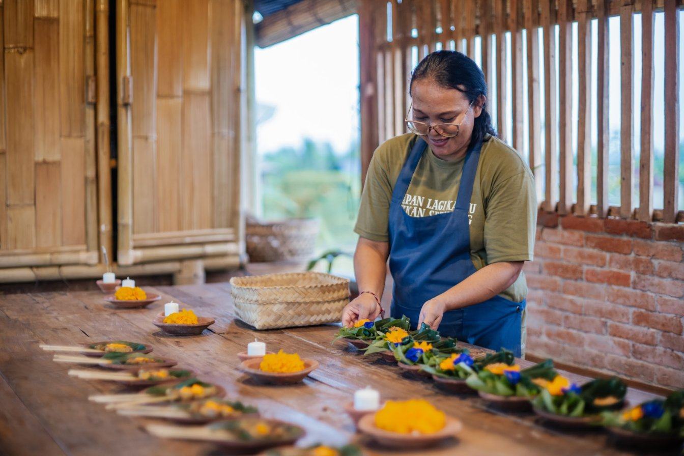 Our cook setting out banana-leaf dishes on a long wooden table