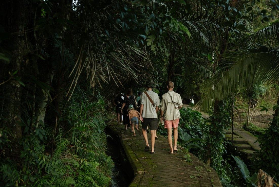 A family walking with their guide along a jungle irrigation canal