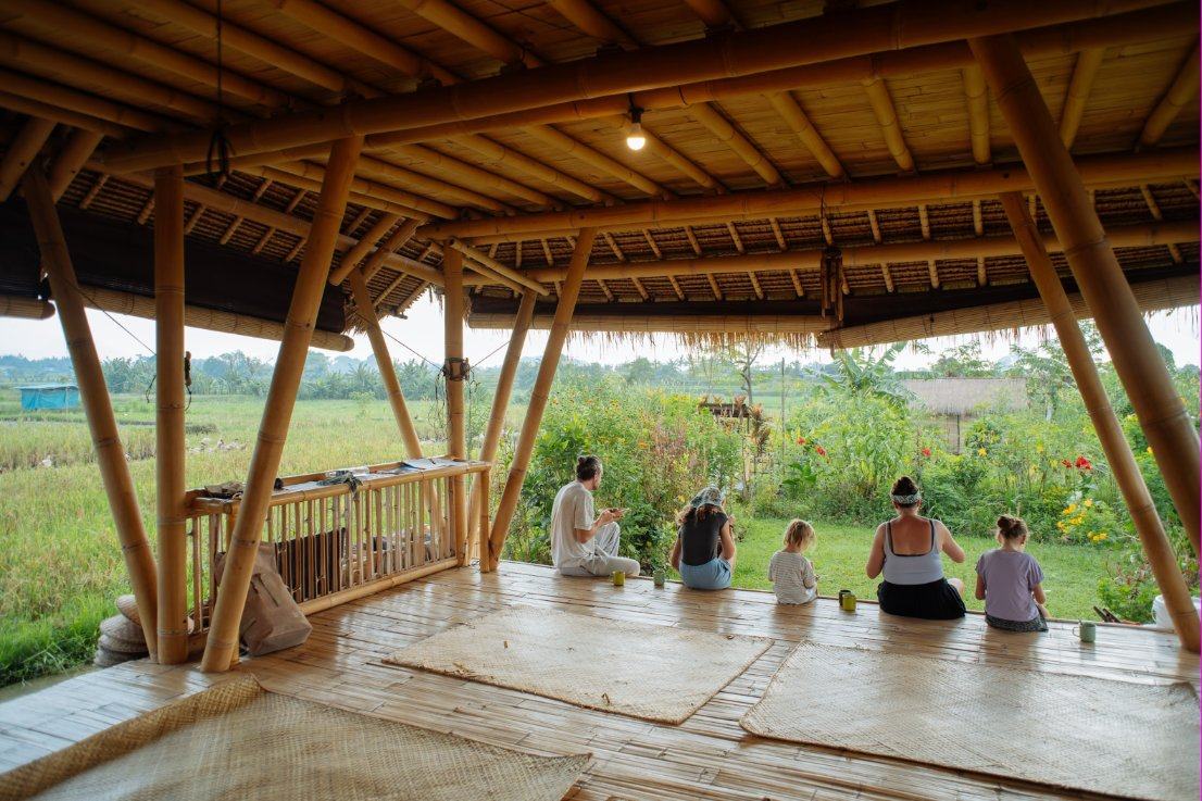 A family sitting on the edge of our bamboo pavilion, looking out over the garden