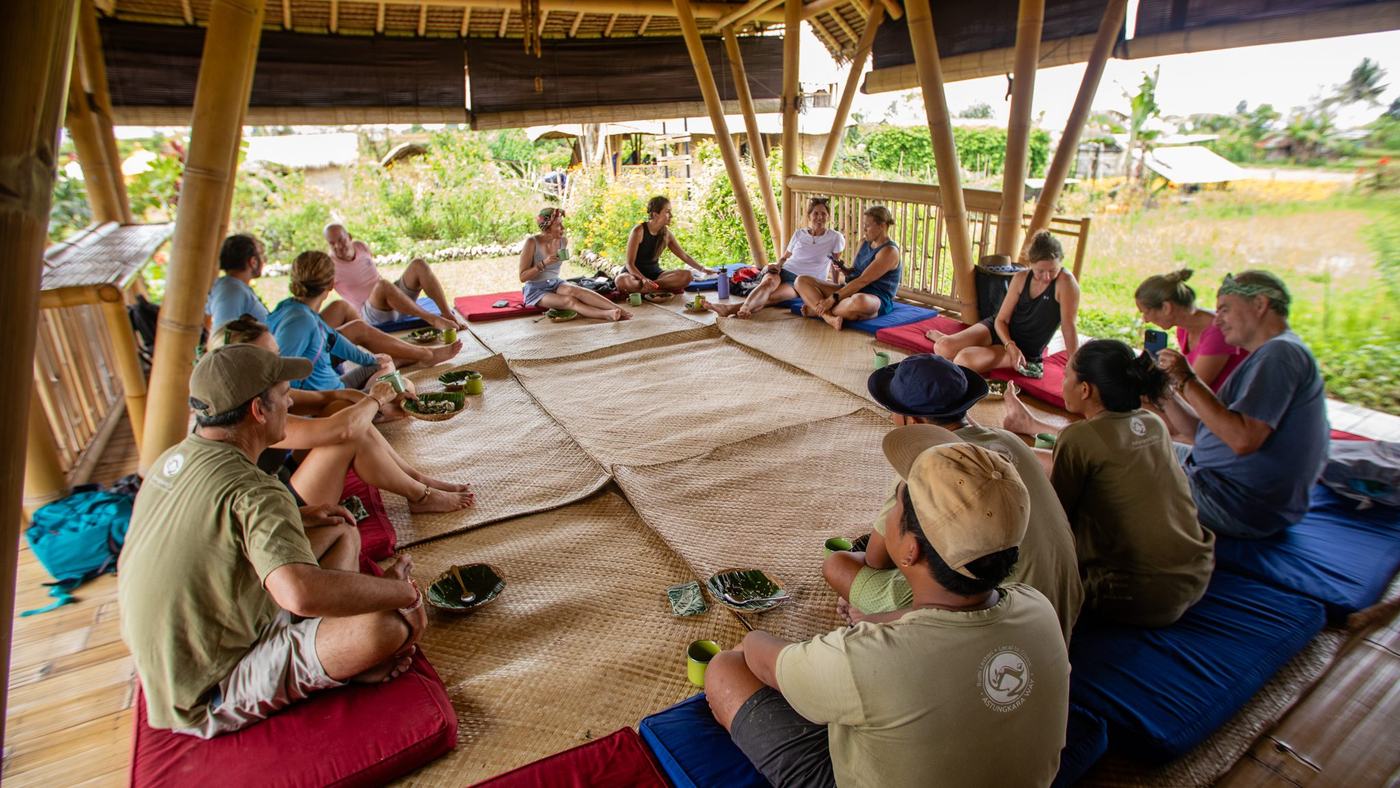 A group seated in a circle on cushions in the bamboo pavilion