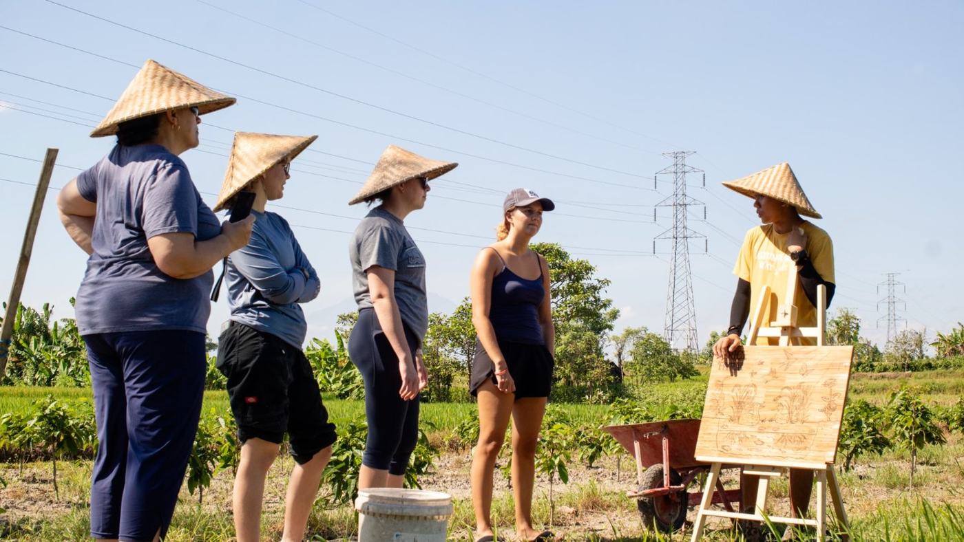 A group in woven hats listening to our guide on a farm tour in our fields