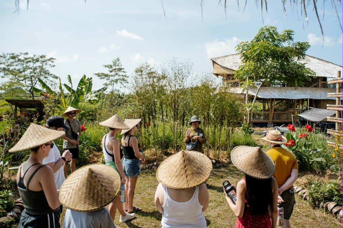 A group in woven hats listening to our guide in the garden at our learning centre