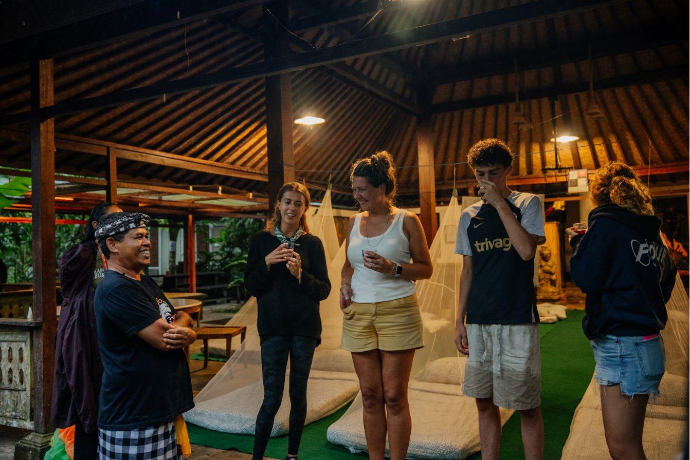 Pilgrims and a host sharing a drink at dusk under the pavilion
