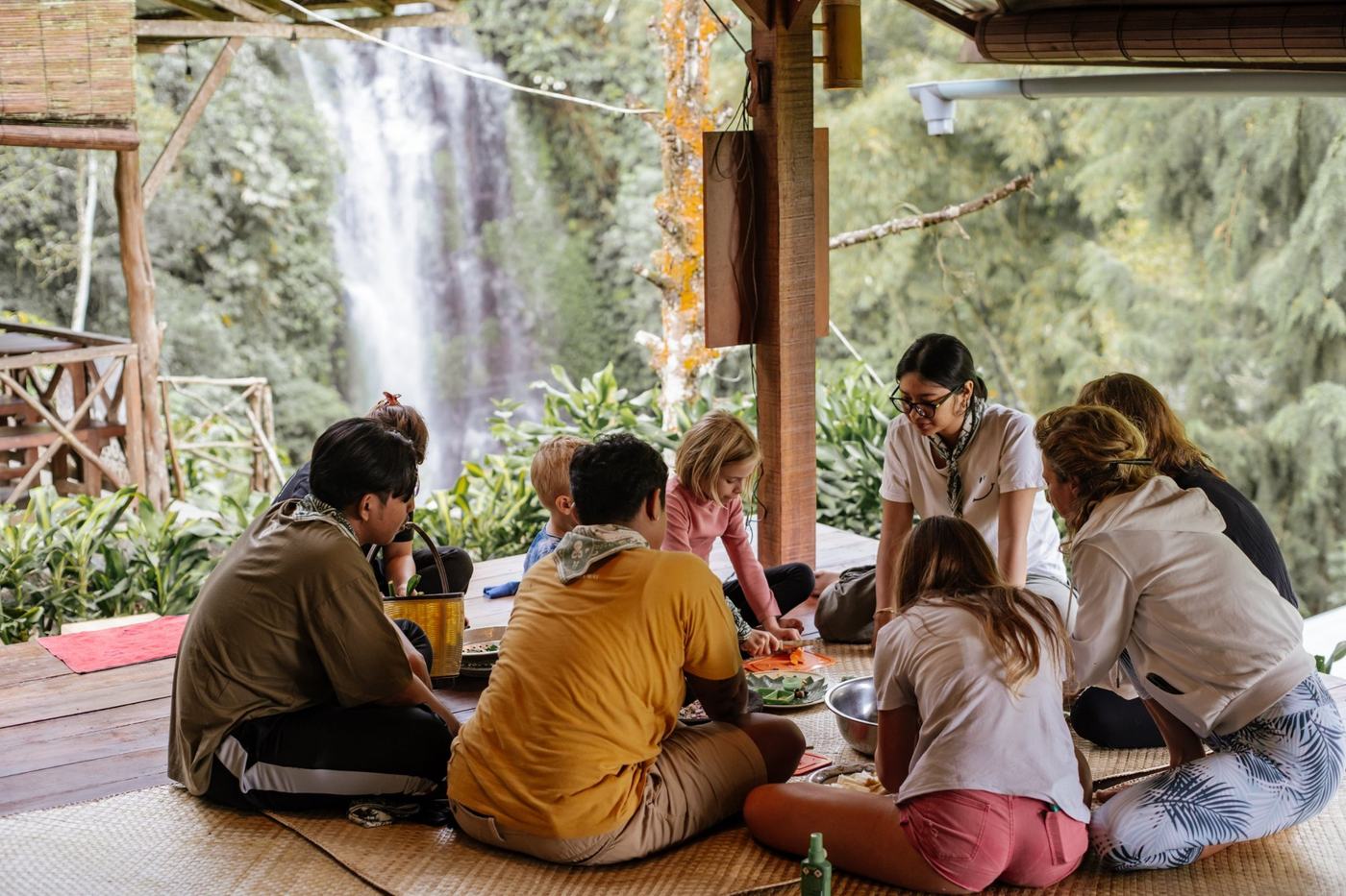 Pilgrims and hosts preparing food on a platform facing the waterfall