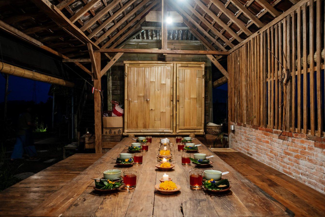 A long table set with candles and banana-leaf plates for dinner