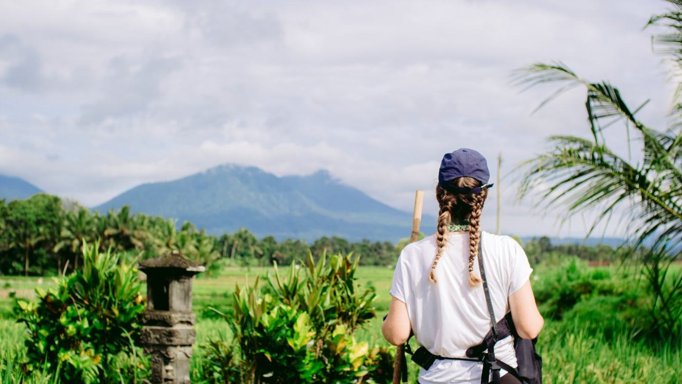 A pilgrim looking out over the rice fields towards a volcano in Bali