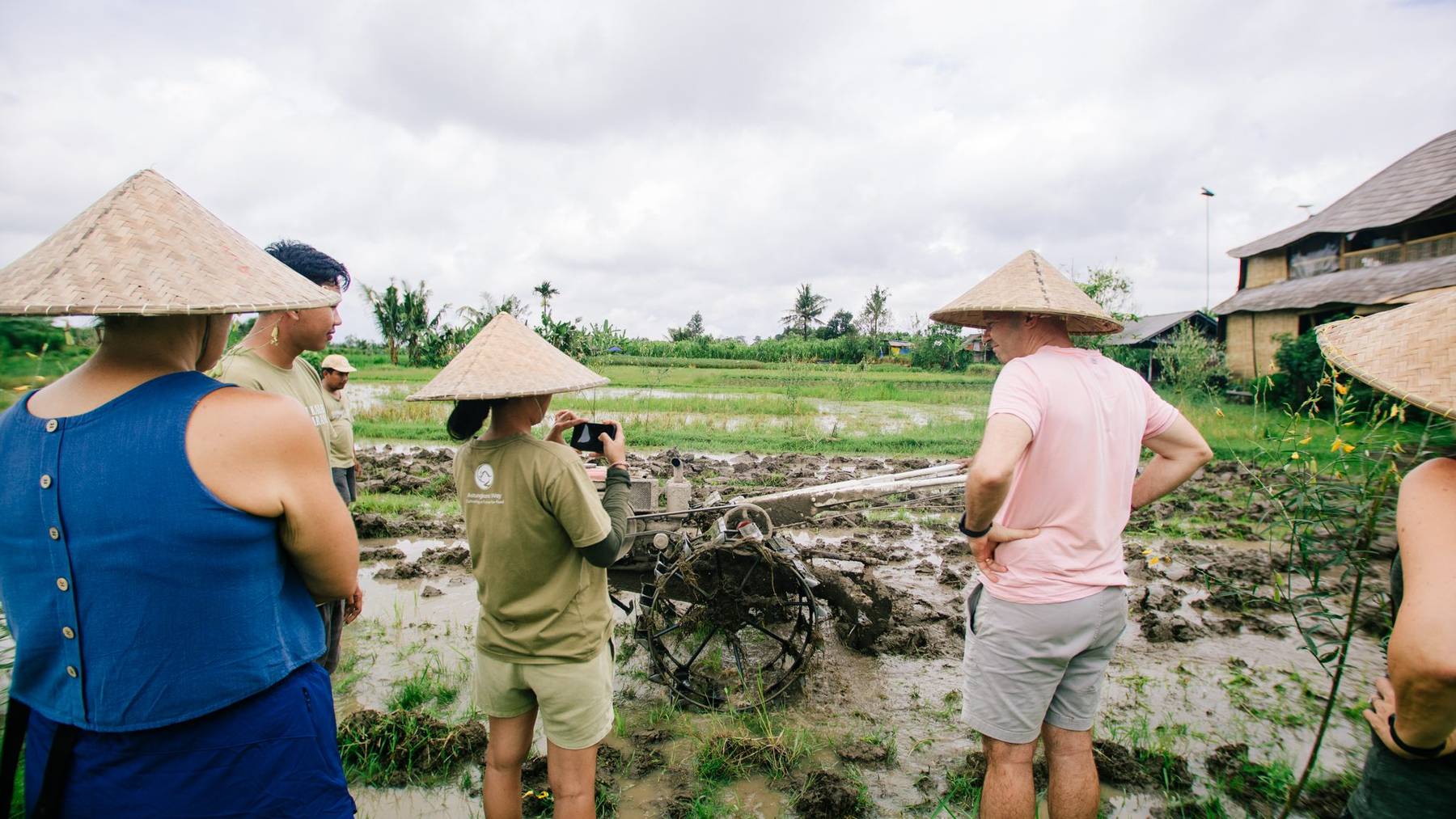 People in woven hats at the edge of a flooded rice field
