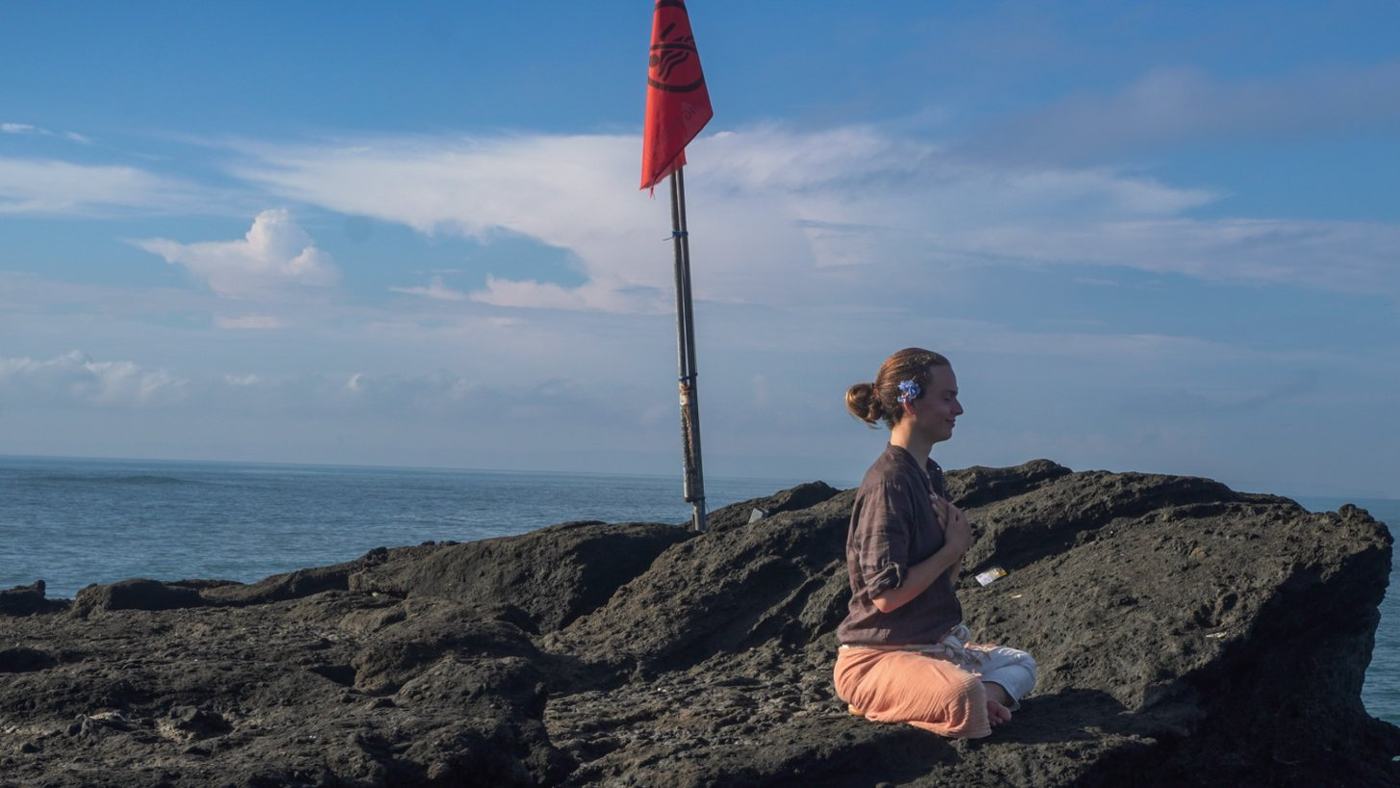 A pilgrim in quiet reflection on the rocks of the south coast at the start of the trail