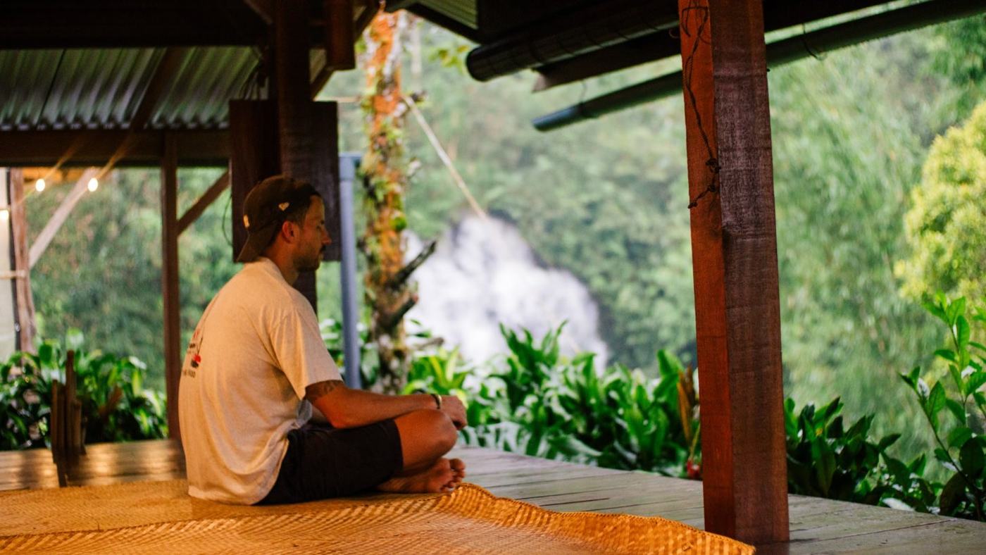 A pilgrim sitting on the open-air platform facing the waterfall