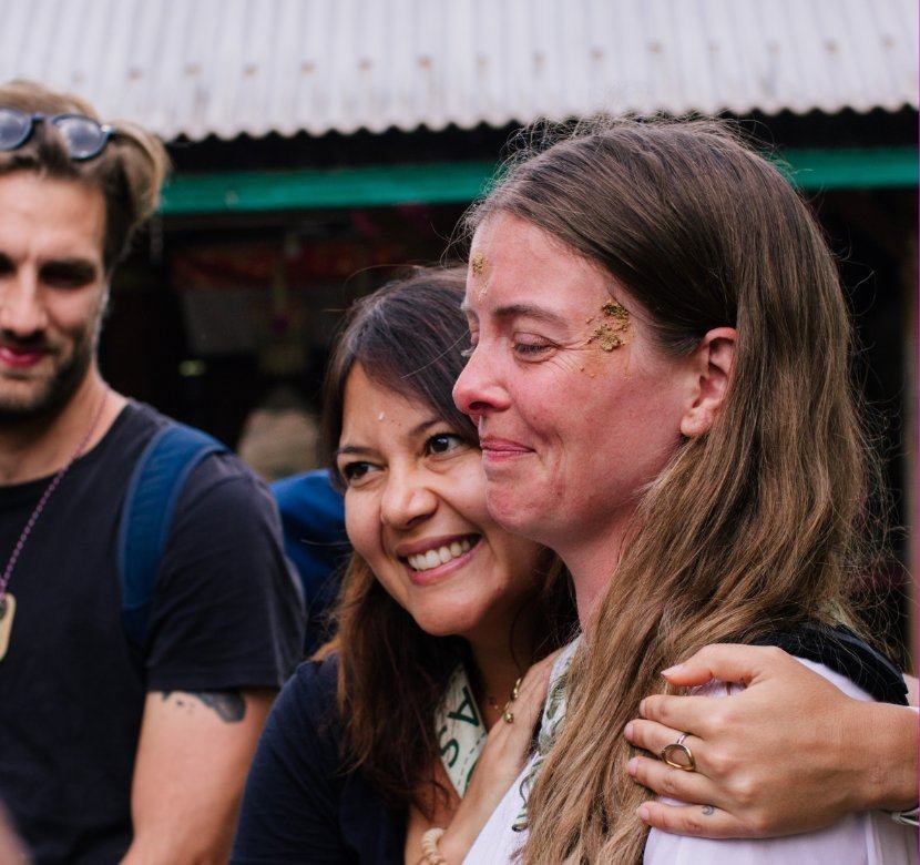 Pilgrims smiling after a water blessing, rice grains on their foreheads