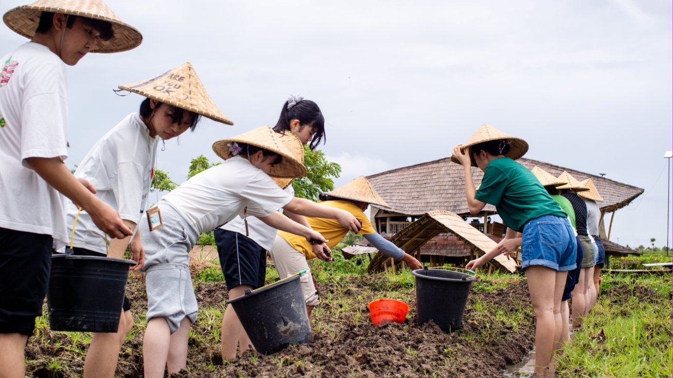 Students in woven hats planting in the fields at our learning centre